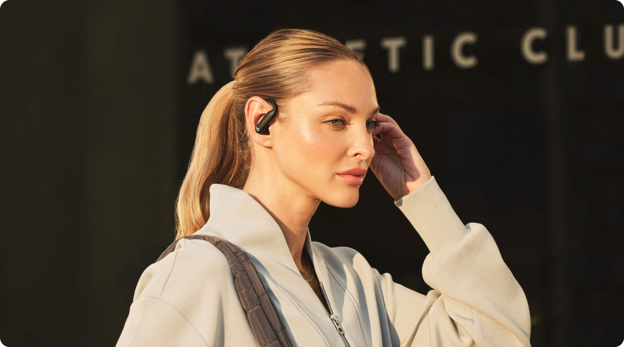 Kona gengur um borgarumhverfi með Powerbeats Pro 2 í eyrunum.